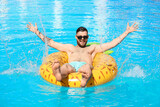 Fototapeta  - Young man with inflatable ring in swimming pool
