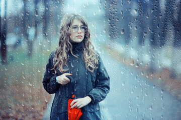 seasonal autumn pornetret, sad girl behind wet glass, raindrops background