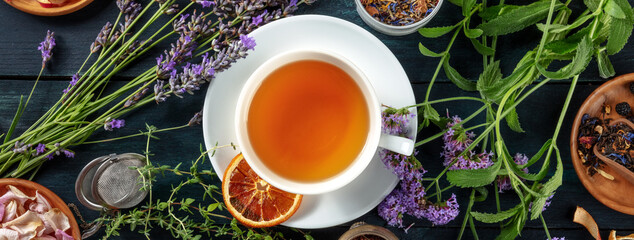 Wall Mural - Tea panorama with herbs, flowers and fruit, shot from the top on a dark rustic wooden background