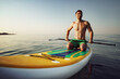 © fotofabrika - Young fit man on paddle board floating on lake.