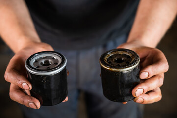 An auto mechanic holds a new and used oil filter.