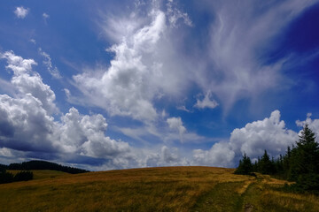  wonderful different clouds on a blue sky over a hilly mountain while hiking