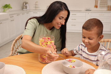 Sticker - Happy mother feeding her son at table in kitchen