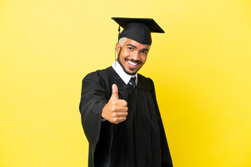 Poster - Young university graduate Colombian man isolated on yellow background with thumbs up because something good has happened