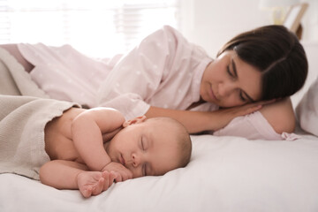 Sticker - Young mother resting near her sleeping baby on bed at home