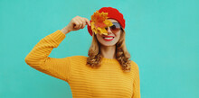 Autumn Portrait Of Happy Smiling Young Woman With Yellow Maple Leaves Wearing A Knitted Sweater, Red Beret On Blue Background