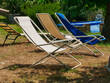 white and blue deck chairs on a meadow with parched grass. In summer in Tuscany, Italy