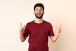© luismolinero - Young Moroccan man isolated on beige background surprised and pointing up