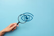 A person examines the eye through a magnifying glass. Symbol for the diagnosis of eye diseases