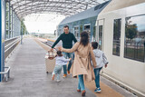 Full length of happy woman and two little kids meeting father on railroad station platform