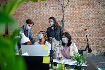 Wall Mural - Young and old architects feeling joyful at desk in office, cooperation and coronavirus concept.