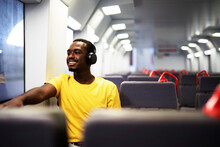 Young Man Travel By Train. Handsome African Man Listening The Music While Travel.