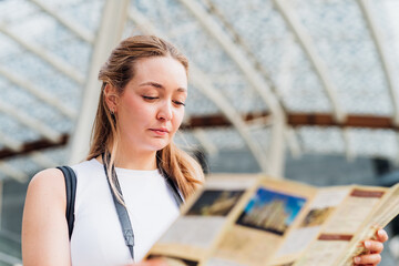 Young caucasian woman traveller holding tourist map smiling discovering and sightseeing