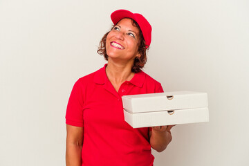 Middle age delivery woman taking pizzas isolated on white background dreaming of achieving goals and purposes