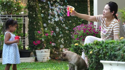 Wall Mural - A mom with bulldogs and her cute little girl blowing bubbles in the yard