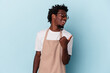 Young african american store clerk isolated on blue background points with thumb finger away, laughing and carefree.