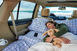 A young woman sleeps in a hugging with a stuffed rabbit in the car by the ocean.