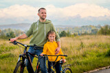 Fototapeta Przeznaczenie - Happy father and daughter take bike ride in nature in autumn.