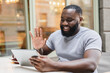 © InsideCreativeHouse - Young african male student freelancer businessman talking on video call conversation online using digital tablet, working remotely on distance outdoors in city cafe