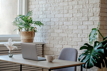 Wall Mural - Creative workspace of a blogger. Laptop computer on wooden table in loft style corner office with brick walls and big windows. Designer's table concept. Close up, copy space, background.