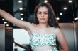 © Migue Suarez - Muchacha trabajadora de pelo castaño morena pulsando las teclas del ascensor para acceder a una reunión de empresa con vestido de verano