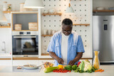 Fototapeta  - Senior African man standing in the kitchen and preparing a healthy dinner.