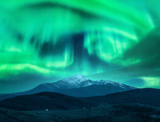 Wall Mural - aurora borealis over the snow covered mountain peak in europe. northern lights in winter. night land