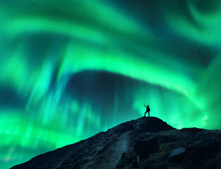 Wall Mural - northern lights and silhouette of standing woman with raised up arms on the mountain. aurora boreali