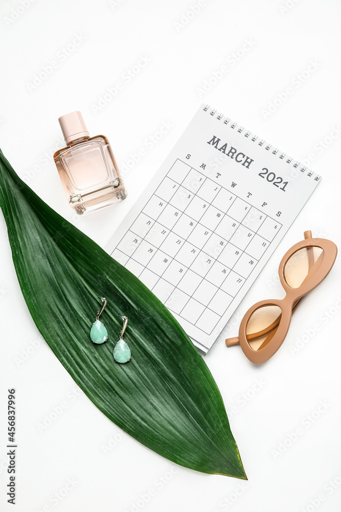 Calendar with female accessories and tropical leaf on white background