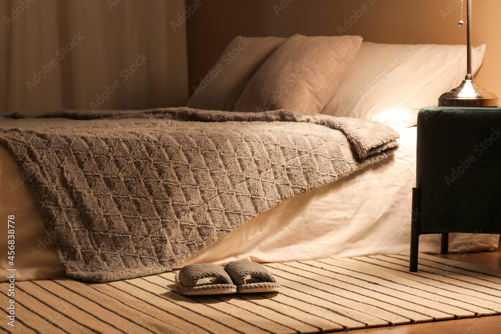 Female soft slippers on rug near bed