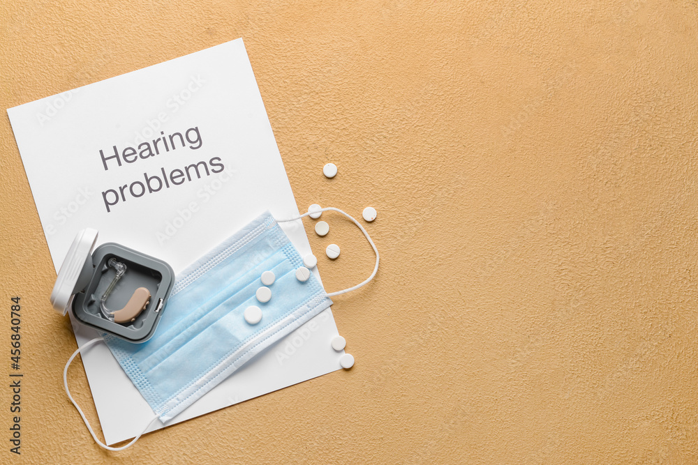 Text HEARING PROBLEMS with aid, medical mask and pills on color background