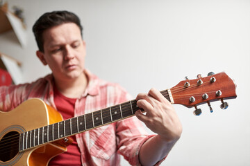 Young man learning to play the guitar at home.