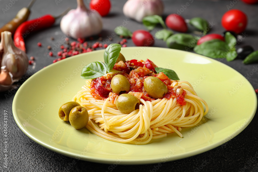 Plate with tasty Pasta Puttanesca on dark background