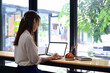 © Prathankarnpap - Back view young woman sitting in cafe and using laptop computer.