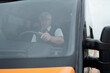 © pressmaster - Behind windshield view of serious aged Caucasian bus driver in glasses sitting at wheel