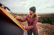 © StratfordProductions - Young beautiful woman making and building a tent in the mountain while camping during winter