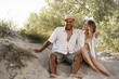 © fotofabrika - Young couple sitting next to each other on beach