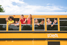 Group Of Young Students Attending Primary School On A Yellow School Bus