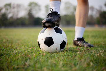 Sports and recreation concept a male soccer player wearing black t-shirt and pants practicing kicking the ball in the grassy field