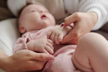 Wall Mural - Hands of young mother calming cute baby down while lulling her after feeding