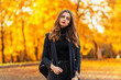 © alones - Autumn portrait of a pretty young woman with red lips in a black elegant suit with a blazer and sweater walks in the park with colored golden fall foliage at sunset