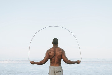 Wall Mural - Fit man jumping rope at the beach