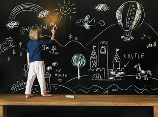 Cute little girl drawing on a blackboard