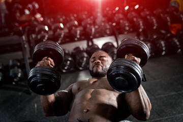 Handsome power athletic man bodybuilder doing exercises with dumbbell. Fitness muscular multiracial man training at the gym. Fitness concept