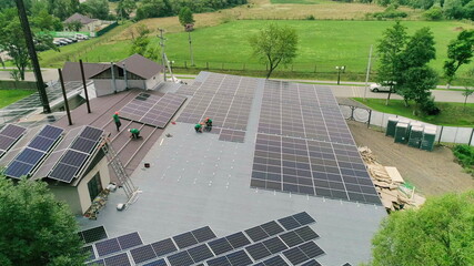 Workers installing solar panels on the roof of a house,which converts solar energy. Workers in special outfit talk about sunny cells installation. Translation: the name of the city of Luzhansky 2