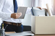 personnel packing personal belongings and files into a brown cardboard box with resignation letter for changing and resign from work concept for quit or change of job