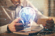 © peshkova - Double exposure of man's hands holding and using a digital device and bulb hologram drawing. Idea concept.