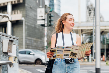 Young caucasian woman photographer traveller holding tourist map smiling discovering and sightseeing