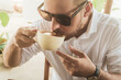 Mężczyzna pijący kawę w kawiarni w słoneczny dzień.