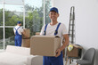 © New Africa - Moving service employees with cardboard boxes in room